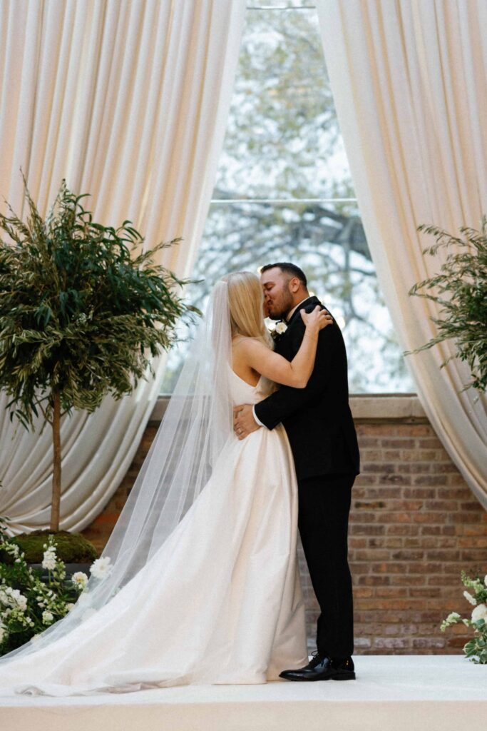 A bride and groom share their first kiss during the wedding ceremony in Chicago at the Bridgeport Art Center.