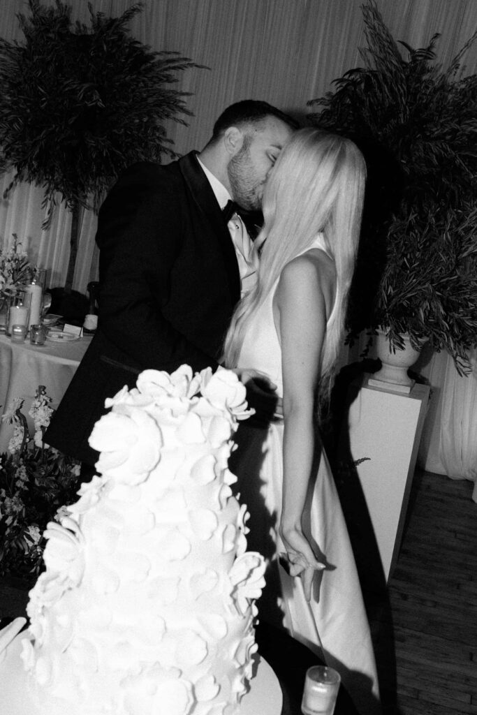 Bride and groom kiss in front of their wedding cake at Bridgeport Art Center.