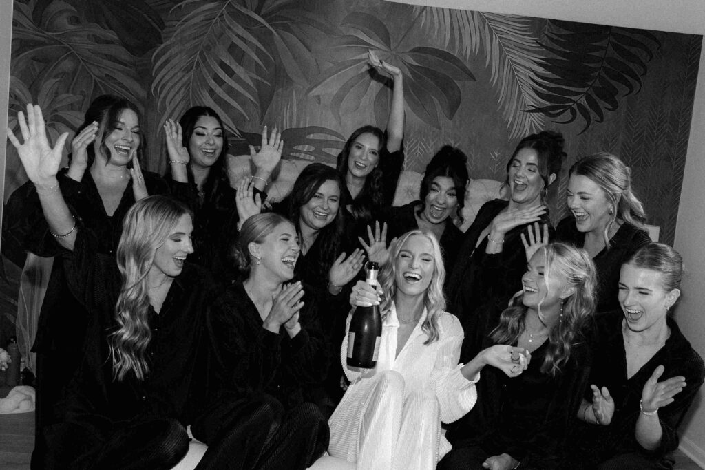 Bridal party cheering on the bride with a bottle of champagne on the day of her Chicago wedding.