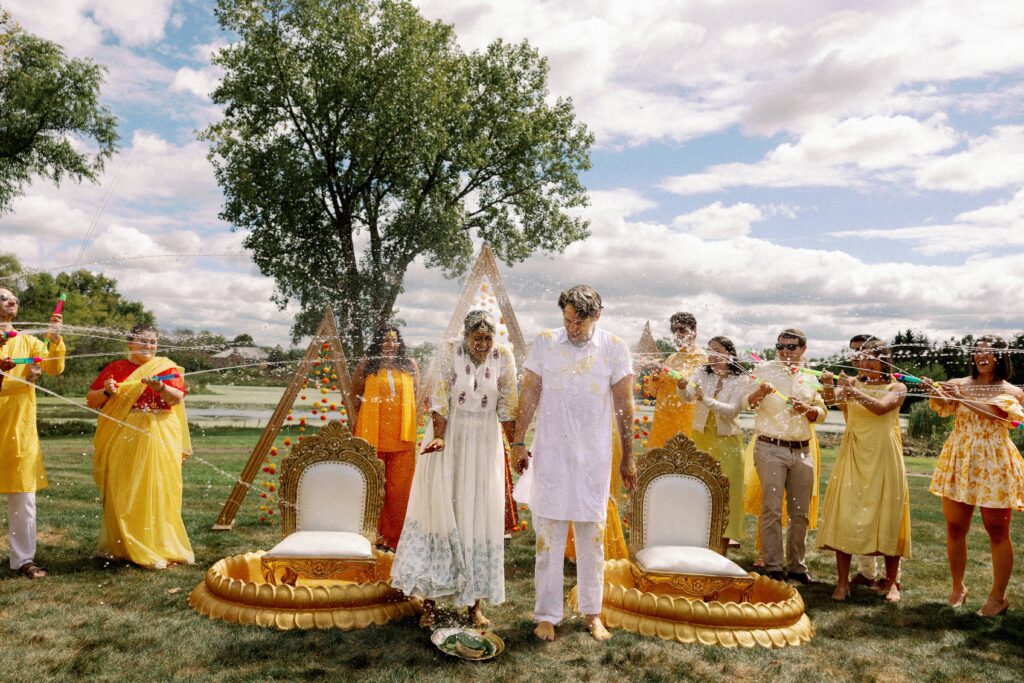 Indian wedding party splashing water on the bride and groom during their water ceremony.