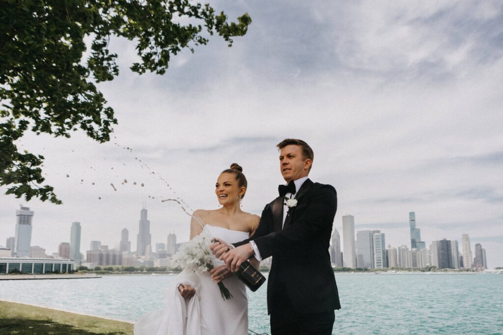 Bride and groom pop champagne with Lake Michigan in the background.