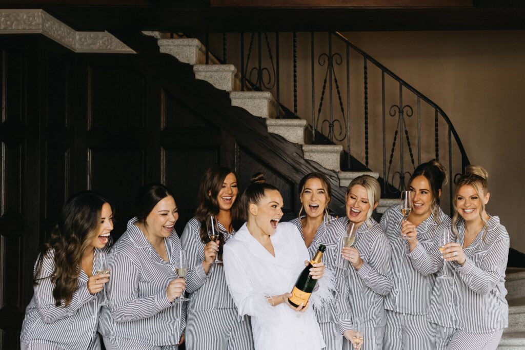 The bride and her bridesmaids enjoying a drink and laughing as they get ready in the Revel Space guest suites.