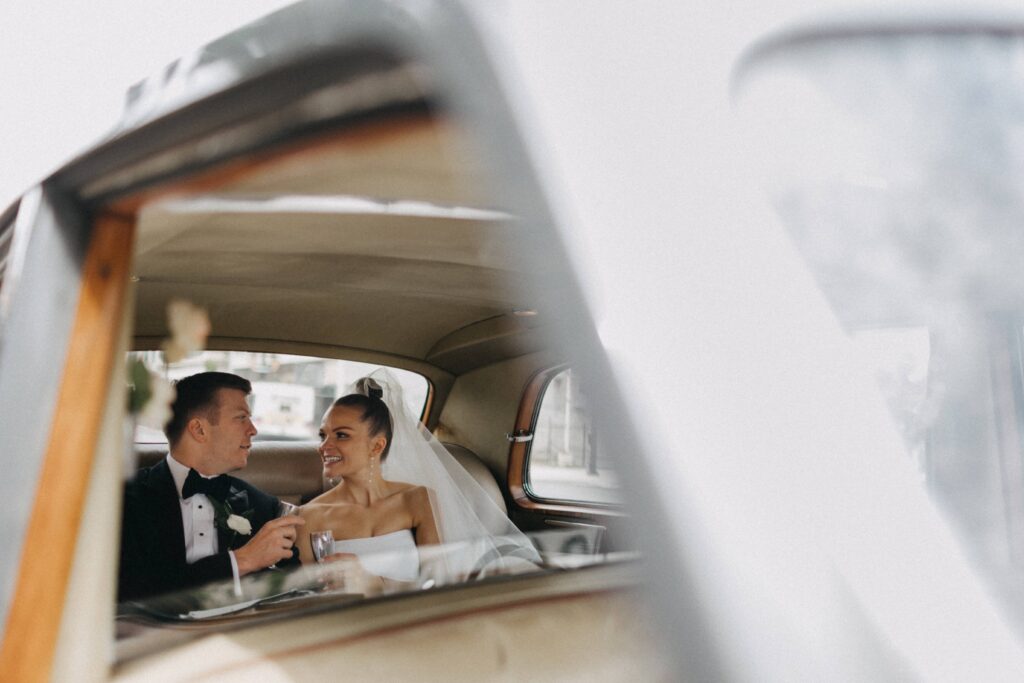 Bride and groom in the backseat of a Rolls Royce as they depart from their wedding at Revel Space.