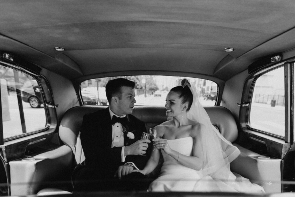 Black and white modern vintage photo of the bride and groom in the back of a Rolls Royce after their Chicago wedding held at Revel Space.