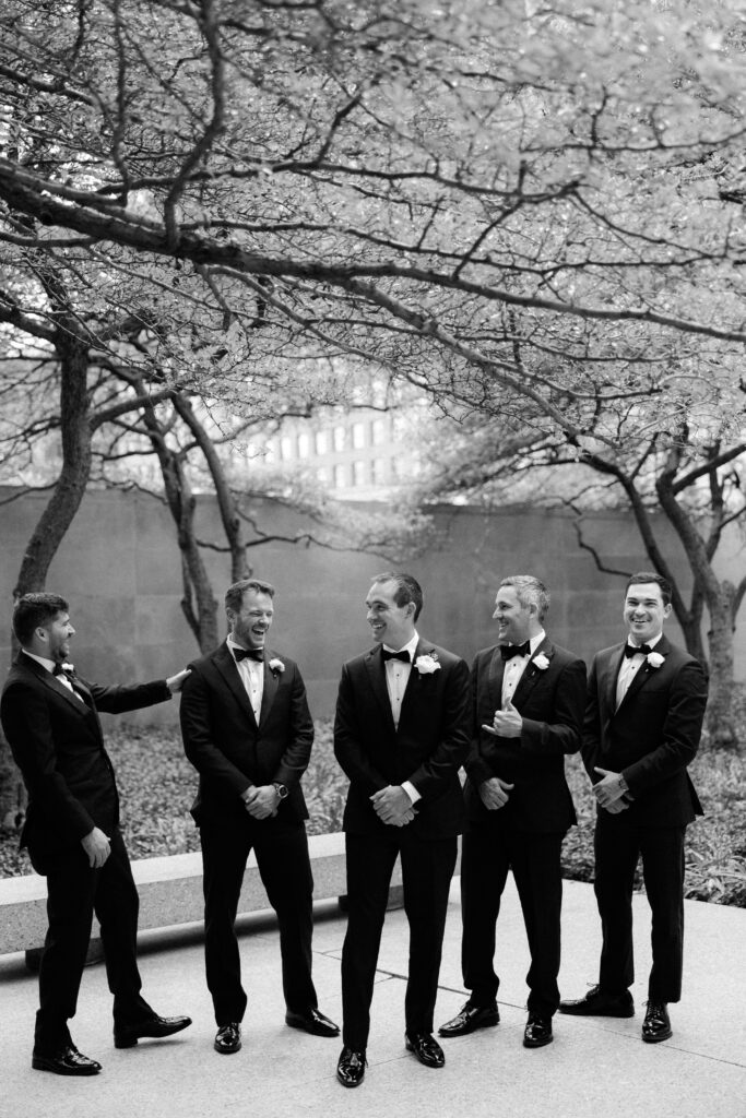 Groomsmen laugh in black and white photo
