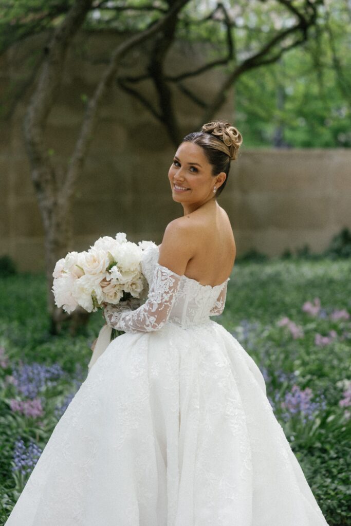 Bride smiles at the camera and holds wedding bouquet